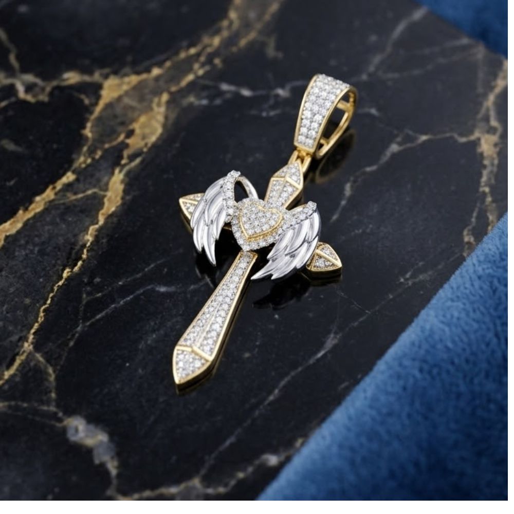 The 1 1/5CTW Natural Diamond Chrome Hearts Cross Charm in 10K gold, with angel wings and a heart at the center, is shown on black marble with gold veining and a blue textured edge—ideal for hip hop jewelry fans.