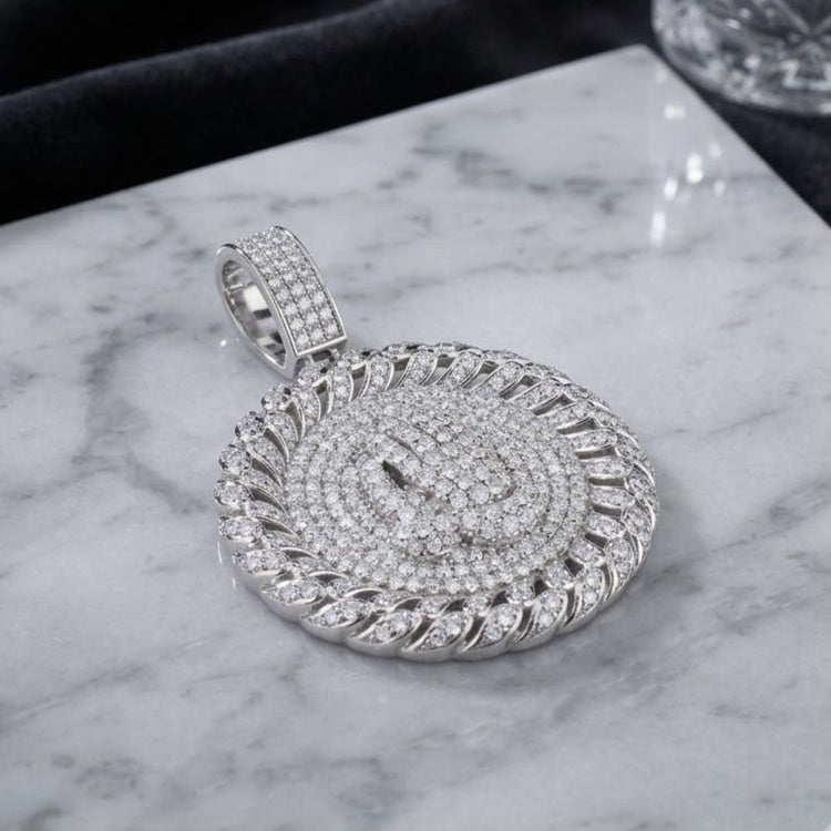 A Sterling Silver Moissanite Praying Hands Pendant, crafted in 925 sterling silver, rests on a white marble surface. This men’s pendant features a detailed, layered design with sparkling moissanite stones on the bail and intricate, braided edges—seamlessly blending classic craftsmanship with modern style.