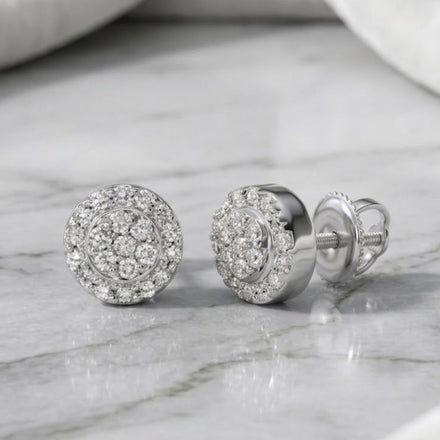 A pair of 1/10CTW diamond round earrings in sterling silver, featuring a cluster design, elegantly displayed on a marble surface.