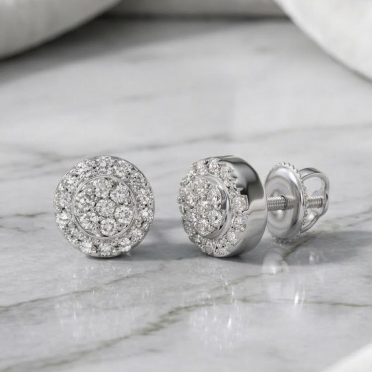 A pair of 1/10CTW diamond round earrings in sterling silver, featuring a cluster design, elegantly displayed on a marble surface.