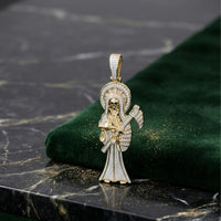 The 1-3/4CTW Natural Diamond Santa Muerte Charm in 10K gold features a skeletal figure with a halo and scythe, adorned with natural diamonds, and is displayed on dark green velvet atop a black marble tabletop.
