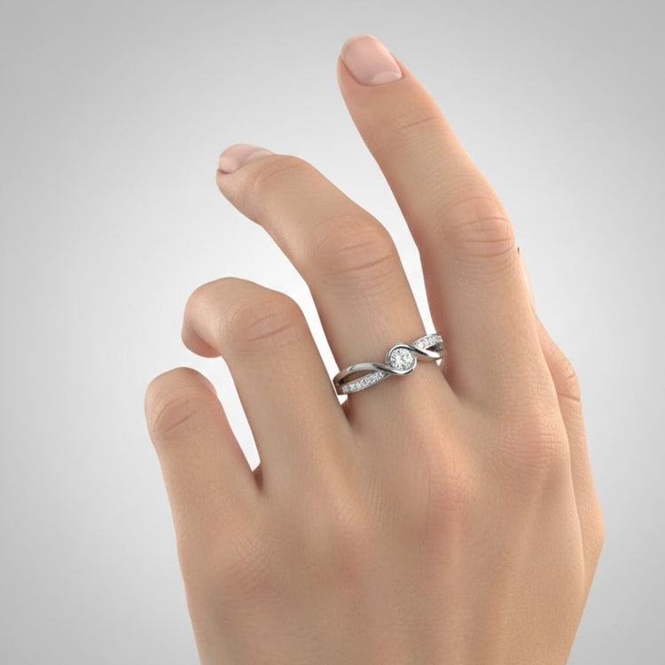 A light-skinned hand wears the Engagement Twist Ring - Lab Diamond, featuring a round lab-grown diamond and an elegant twisted silver band on the ring finger, set against a plain gray background.