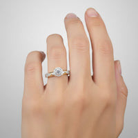 A hand with neatly manicured nails showcases the 1/3CTW Diamond Round Single Halo Engagement Ring in 10k gold, featuring a round sparkling diamond encircled by a halo of smaller diamonds on the ring finger, set against a plain light background.