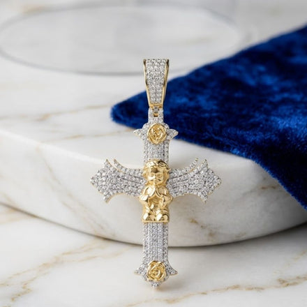 The 1CTW Diamond Angel Cross Charm in 10K gold for men features a central angel figure and rests on white marble beside royal blue velvet—a bold, elegant accessory.