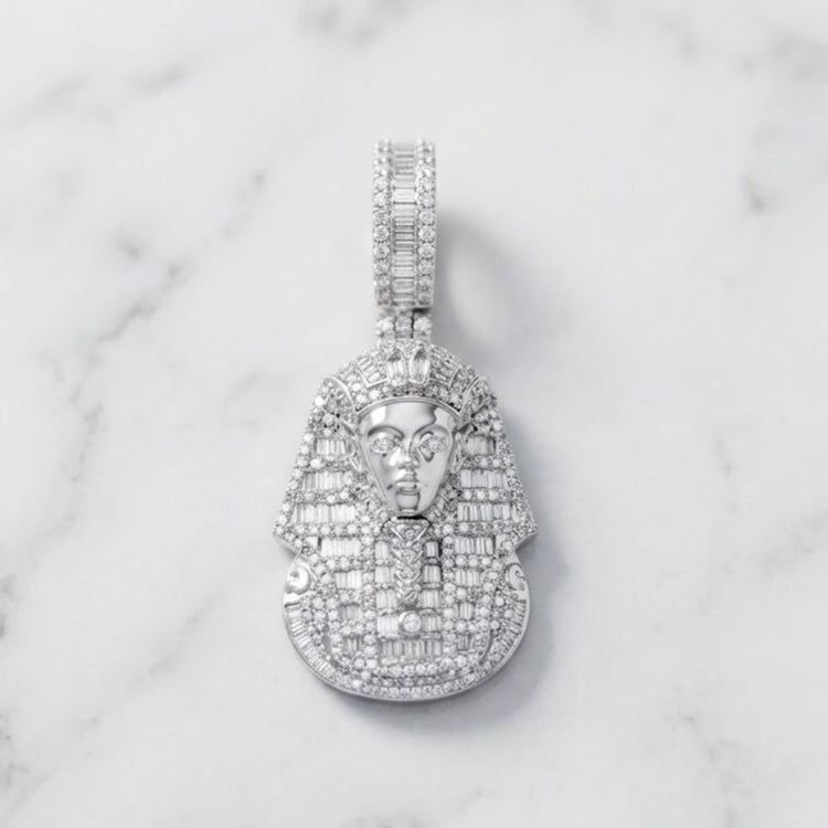 A striking hip hop jewelry piece, the Sterling Silver Round Diamond Pharaoh Charm Pendant 2-1/2 Cttw features a pharaoh’s head design adorned with numerous small diamonds and is elegantly displayed on a white marble surface.