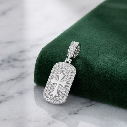 The 925 Silver Moissanite Cross Dog Tag Pendant for men, crafted from sterling silver and adorned with moissanite stones, features a cross cutout and rests on green velvet over white marble—a refined piece of men's religious jewelry.