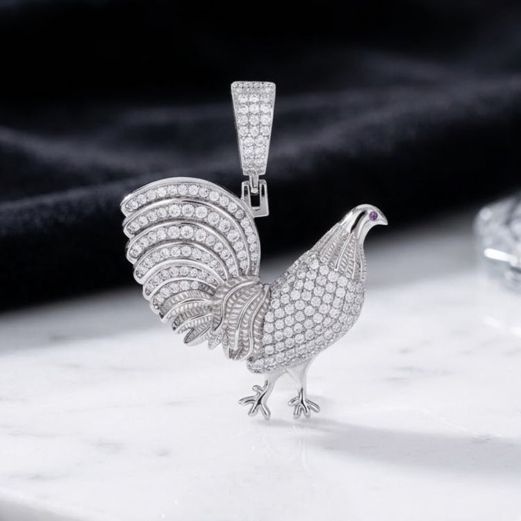 The Sterling Silver Men’s Moissanite Rooster Pendant is showcased on a white marble surface with a black fabric backdrop, creating a bold piece of wildlife-inspired jewelry ideal for those searching for an elegant men’s pendant.