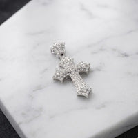 The 1/4 CTW Natural Diamond Cross Pendant in 10K Gold, encrusted with dazzling diamonds, rests on a white marble surface—beautifully crafted for a timeless and elegant gift for any special occasion.