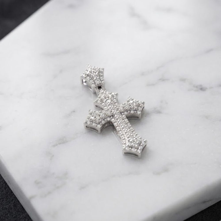 The 1/4 CTW Natural Diamond Cross Pendant in 10K Gold, encrusted with dazzling diamonds, rests on a white marble surface—beautifully crafted for a timeless and elegant gift for any special occasion.