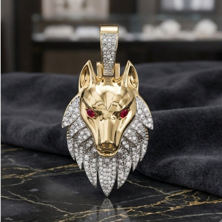 A striking men’s jewelry piece, the 10k Gold Wolf Charm with 7/8CTW Diamonds features red ruby eyes and rests on dark marble, set against a blurred fabric background.