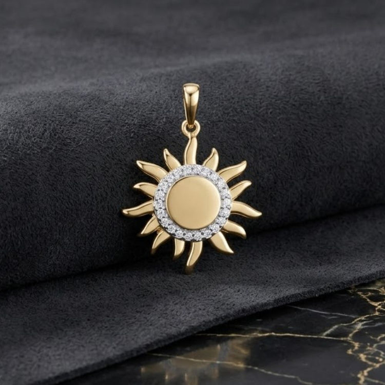 10k Yellow Gold Diamond Gift Pendant 1/10 Cttw, featuring a sun-shaped design with a central circle of sparkling diamonds, is displayed on a dark, textured fabric with part of a marble surface visible.