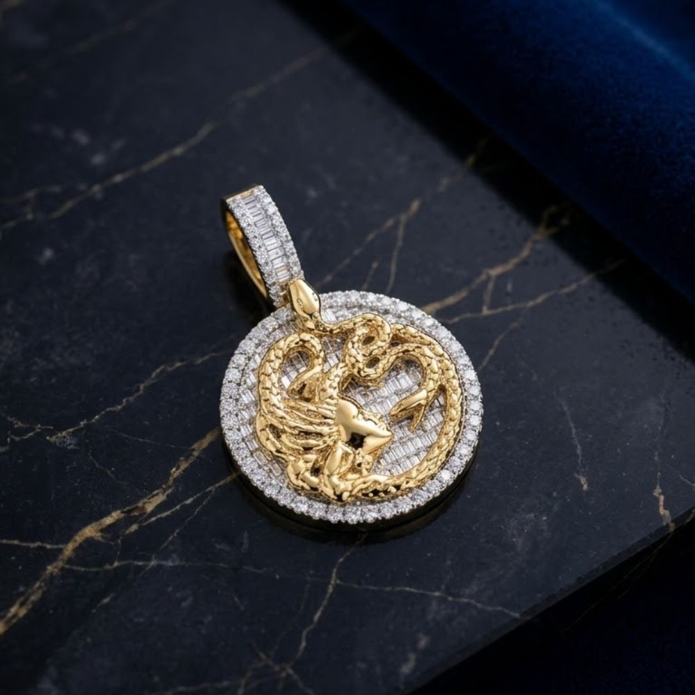 The 10K Gold Baguette Diamond Medusa Snake Charm (2.75 CTW) features a round gold pendant with a raised Medusa design, encircled by sparkling diamonds, displayed elegantly on a black marble surface with gold accents.