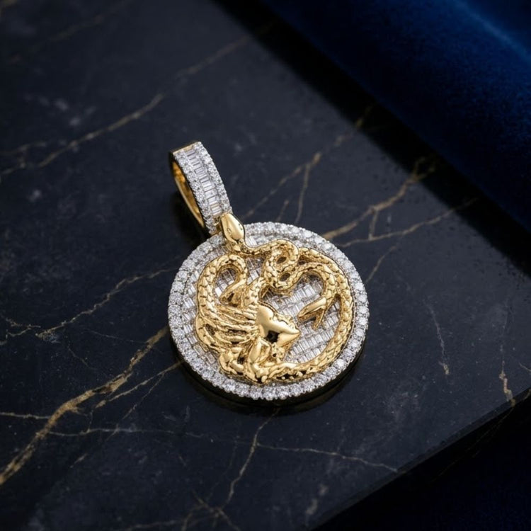The 10K Gold Baguette Diamond Medusa Snake Charm (2.75 CTW) features a round gold pendant with a raised Medusa design, encircled by sparkling diamonds, displayed elegantly on a black marble surface with gold accents.