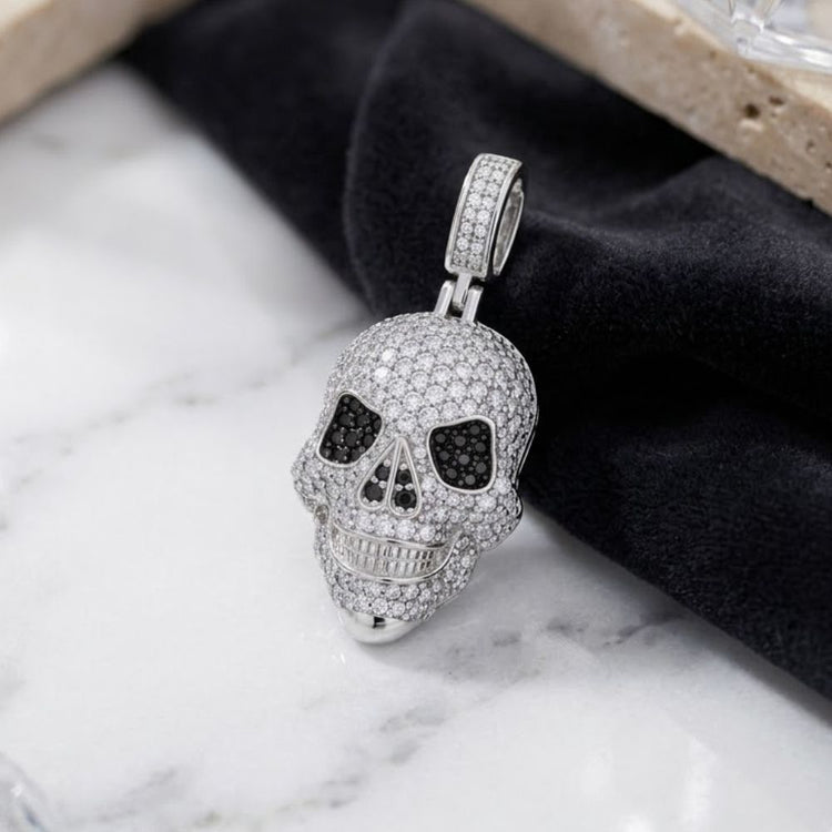 Sterling Silver Black White Moissanite Skull Pendant adorned with dazzling moissanite stones, showcasing bold black gemstone eyes and a radiant finish; elegantly presented on black velvet with a marble backdrop—an eye-catching statement for men’s fashion jewelry aficionados.