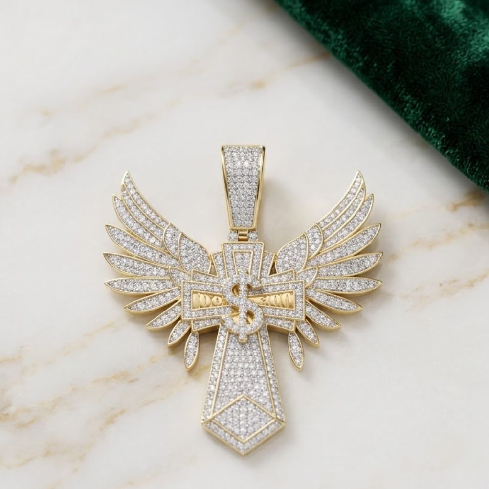 The 10K Gold Diamond Dollar Cross Charm 1.75 CTW, a standout men’s jewelry piece, features diamonds on a gold cross pendant with angel wings, displayed on marble beside green fabric.