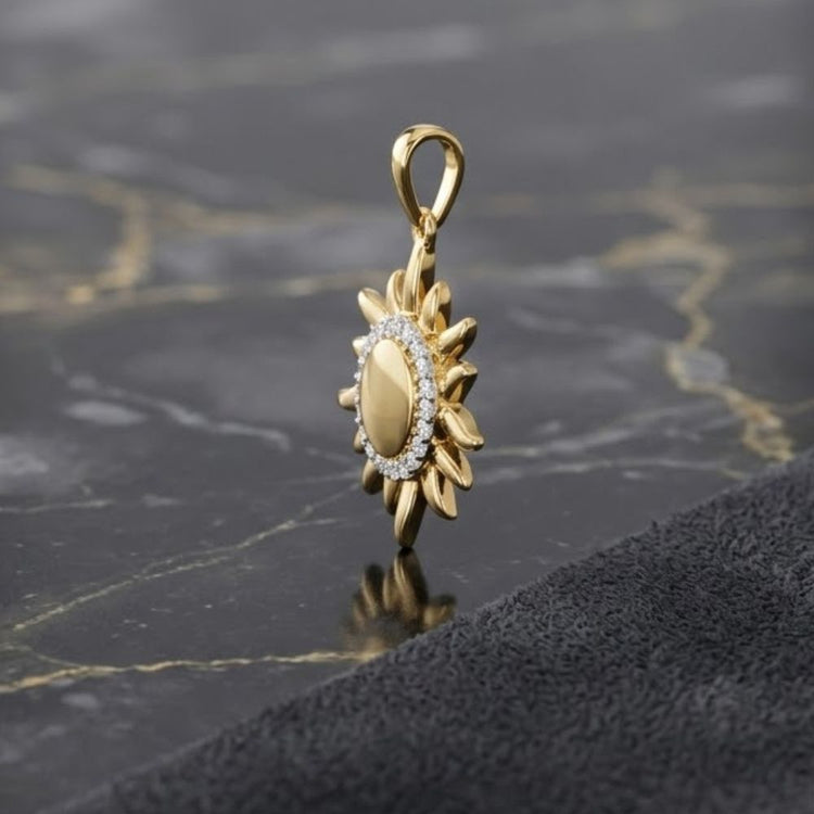 The 10k Yellow Gold Diamond Gift Pendant 1/10 Cttw, featuring a gold sunflower shape with a central oval and a ring of sparkling diamonds, is displayed on a black marble surface beside a textured dark cloth.