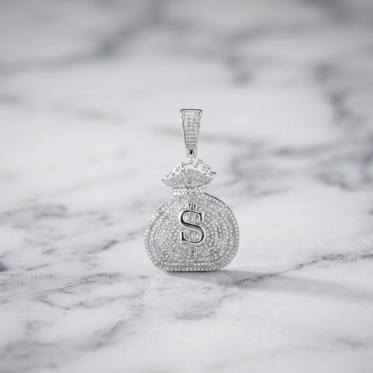 Showcased on a white marble surface, the Diamond Money Bag Pendant 1 CTTW Sterling Silver gleams with a sparkling dollar sign and is adorned with 1 carat total weight of shimmering stones.