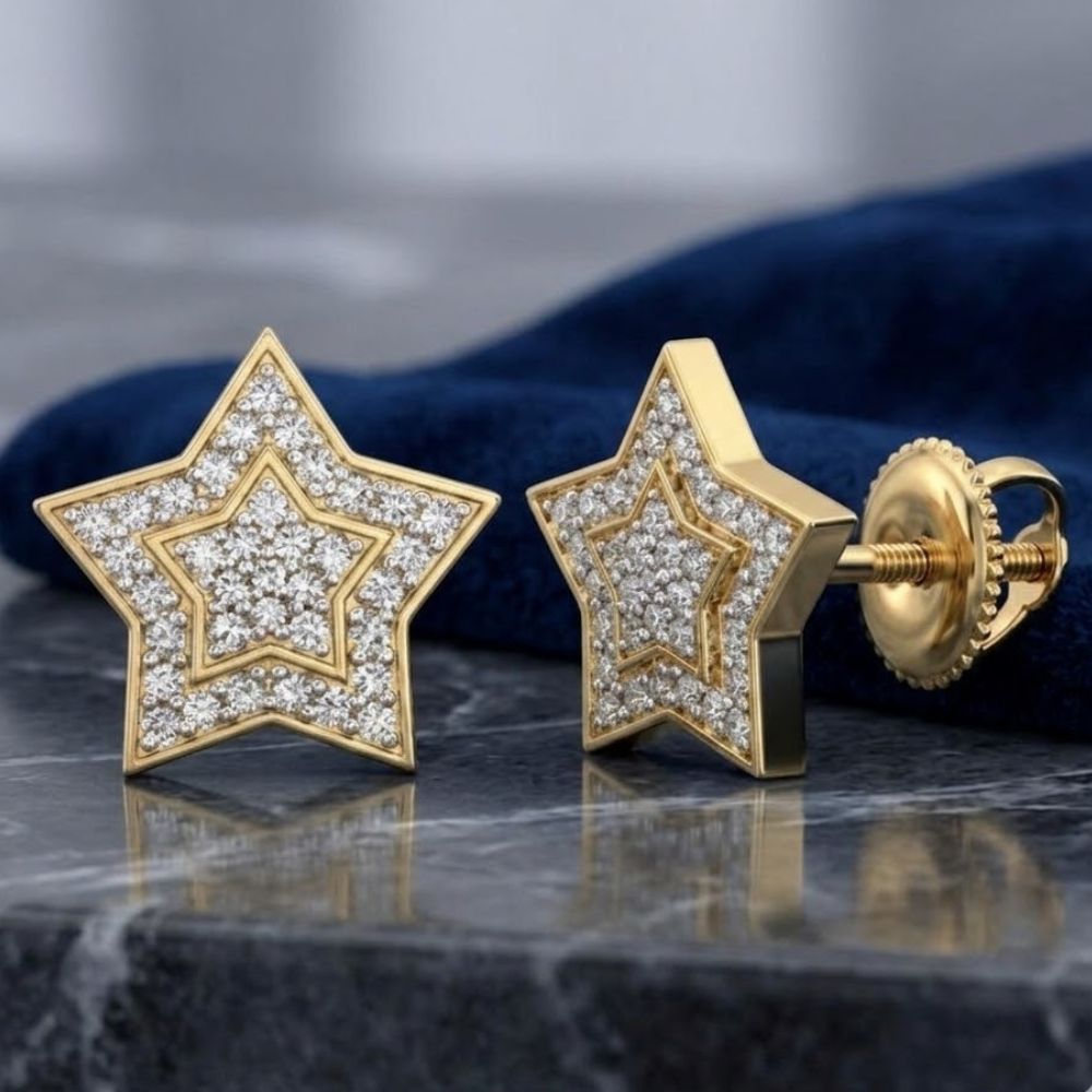 A pair of 10k Yellow Gold Round Diamond Star Earrings (1/5 Cttw) displayed on gray marble with a dark blue cloth in the background.