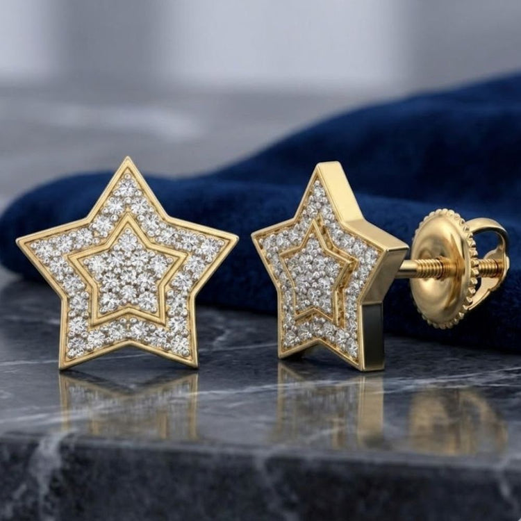 A pair of 10k Yellow Gold Round Diamond Star Earrings (1/5 Cttw) displayed on gray marble with a dark blue cloth in the background.