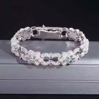 The Flower Design Silver Moissanite Bracelet features sparkling floral details and leaf-shaped gemstones, displayed on a gray surface with a dark background.