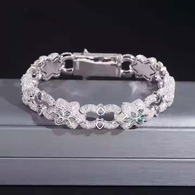 The Flower Design Silver Moissanite Bracelet features sparkling floral details and leaf-shaped gemstones, displayed on a gray surface with a dark background.