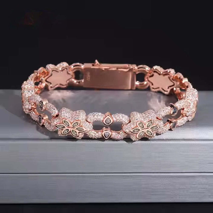 The Flower Design Silver Moissanite Bracelet features delicate floral motifs and sparkling stones, crafted from silver and displayed on a gray surface against a dark background.