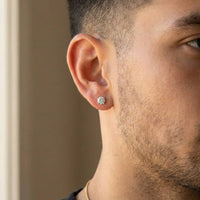 Close-up of a man with short hair, slight facial hair, and a thin gold chain, wearing a 14k Classic Round Lab Diamond Four Prong Stud Earring (F/G VS+). The softly blurred background highlights the sparkling diamond stud.