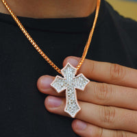 A person wearing a gold chain with the Gothic Lab Diamond Cross Pendant holds the sparkling pendant against their black shirt.