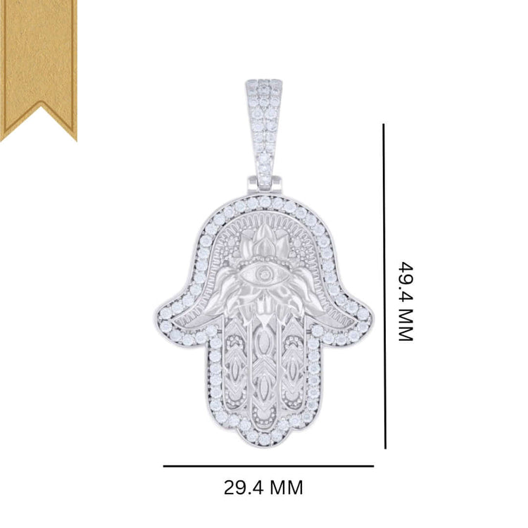 The Moissanite Hamsa Symbol Charm Pendant features an engraved eye design with small clear stones around the border and measures 49.4mm tall by 29.4mm wide, accented by a gold ribbon in the top left corner.