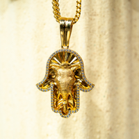 The Hamsa Hand Pendant - 10k features a gold Hamsa hand with an elephant centerpiece, accented by sparkling zircon gemstones, and suspended from a gold chain—a unique jewelry piece.
