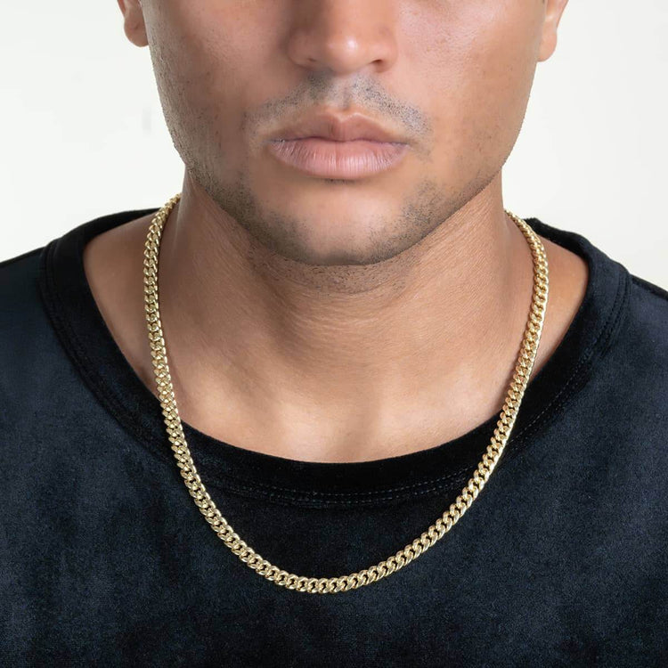 A person wears a black shirt and the Hollow Gold Cuban Link Chain 3mm - 7mm, shown from the shoulders up against a plain background.