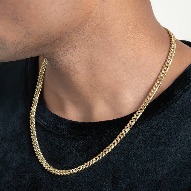 Close-up of a person wearing the Hollow Gold Cuban Link Chain 3mm - 7mm over a black shirt. Only the lower face, neck, and part of the shirt are visible, highlighting the classic curb link design around the neck.