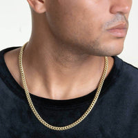 A person wearing a black shirt and a Hollow Gold Cuban Link Chain 3mm - 7mm, shown from the shoulders up with their face partially visible and looking to the side.