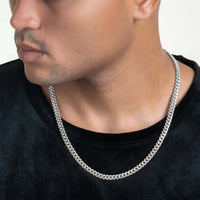A person wears a plain black shirt and the Hollow White Gold Cuban Link Chain 3mm - 7mm, shown from the shoulders up with only the lower half of their face visible. The background is light and neutral.