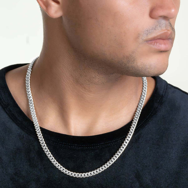 A person in a black shirt wears the Hollow White Gold Cuban Link Chain 3mm - 7mm, shown from the shoulders up with their face partially visible and turned slightly to the side.