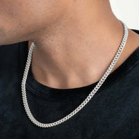 A close-up of someone wearing the Hollow White Gold Cuban Link Chain (7.5mm - 15mm) over a black shirt, with focus on the neck and lower jaw and no full facial features visible.