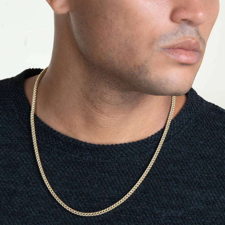 A person wears a textured dark sweater and a Franco Chain - 2mm-7mm Hollow Yellow Gold necklace. The image is cropped to show only the lower half of the face, neck, and upper chest.