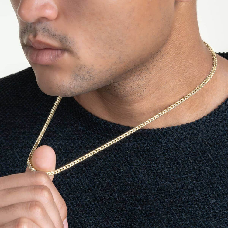A person in a black textured sweater displays the Franco Chain - 2mm-7mm Hollow Yellow Gold around their neck, with only the lower half of their face visible.