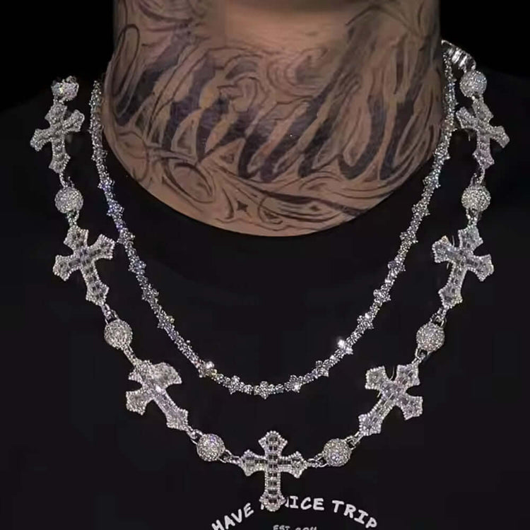 A person with a tattooed neck wears two silver chains—a gleaming Iced Out Moissanite Rosary Ball Chain and another with sparkling crosses—over a black shirt.