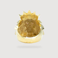 The Indian Men's Medium Ring in 10k gold features an engraved long-haired face with pink gemstone eyes, surrounded by a spiked crown design. Viewed from inside, the ring stands out against a plain light gray background.
