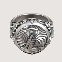 The Masonic All-Seeing Eye Pyramid Illuminati Ring is a silver piece with an engraved pyramid, All-Seeing Eye above it, and decorative swirling patterns with raised details.