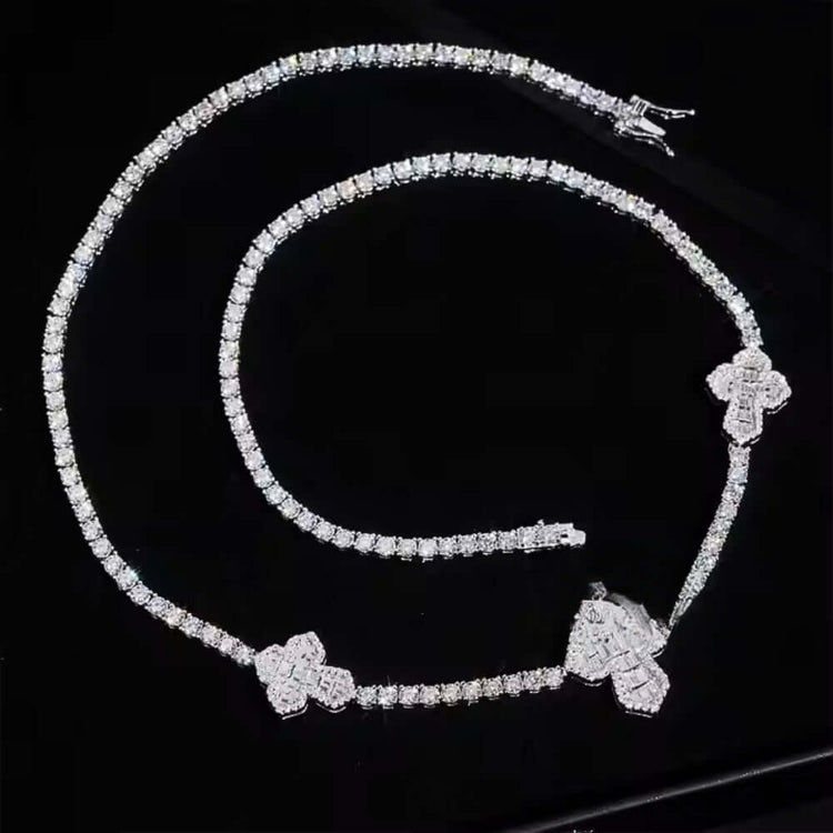 The Iced Out Moissanite Cross Tennis Chain - 3mm and its matching bracelet, both featuring cross-shaped pendants, shimmer elegantly on a glossy black surface.