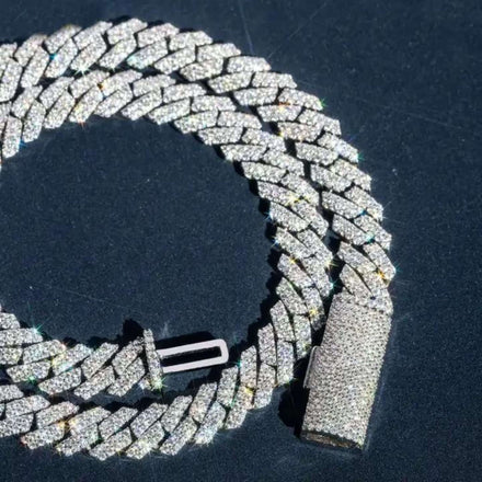 A close-up of the Moissanite Cuban Link Chain 10mm, crafted from 925 sterling silver and encrusted with moissanite stones, arranged in a loose spiral on a dark surface.