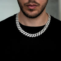 A man with a trimmed beard wears a black shirt and the Moissanite Cuban Link Chain, 12mm-15mm in 925 sterling silver, featuring thick links iced out with sparkling stones.