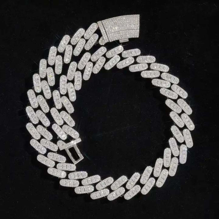 The Moissanite Cuban Link Chain, 12mm-15mm in 925 Sterling Silver, features a rectangular gem-covered clasp and is displayed in a spiral on a black background.