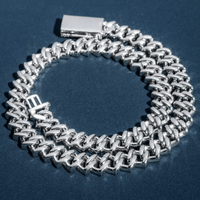 The Moissanite Cuban Link Chain 15mm, crafted in 925 sterling silver, features a rectangular clasp and M-shaped charm—perfect men's hip hop jewelry—shown coiled on a textured dark blue surface.