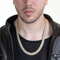 A man in a black shirt and leather jacket showcases the Moissanite Cuban Link Chain 8mm-23mm - Solid Yellow Gold. His partially visible face highlights the sparkling chain's bold, luxurious design.