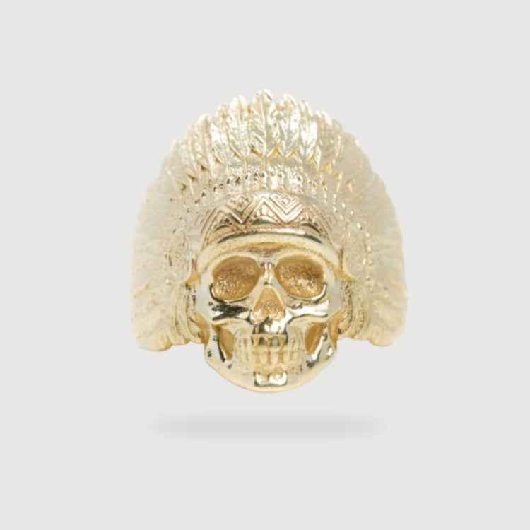 The Native Skull Men Ring – Solid 14K Gold features a skull with a feathered headdress, evoking a Native American chief, and is displayed on a simple light background.