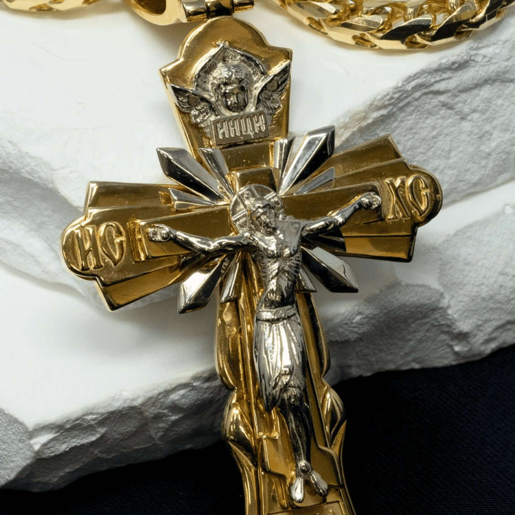 A close-up of the Orthodox Cross Pendant - 14K Gold, featuring Jesus on the cross with detailed craftsmanship and Cyrillic letters, displayed on a white surface.