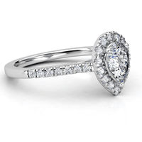 The Pear-Shaped Halo Lab Diamond Engagement Ring with Pavé Band features a pear-shaped lab diamond center, a halo of smaller diamonds, and extra pavé diamonds along a white gold band.